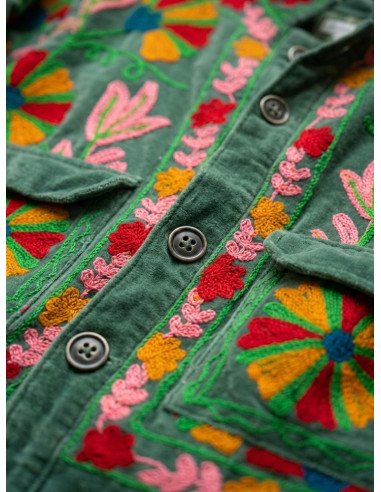 Pormenor em grande plano dos botões e bordados florais multicoloridos em rosa e encarnado no veludo verde do casaco
