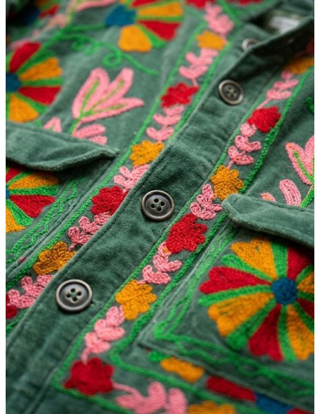 Pormenor em grande plano dos botões e bordados florais multicoloridos em rosa e encarnado no veludo verde do casaco